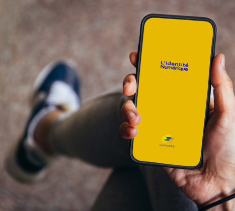 Une main tient un téléphone portable sur lequel on voit l'application L'Identité&nbsp;Numérique se lancer.